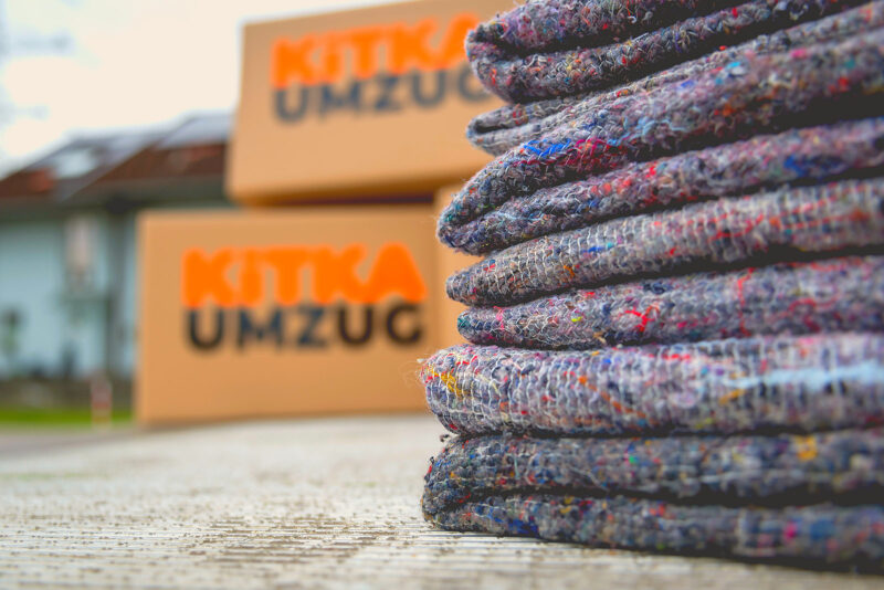 Stapel gefalteter Umzugsdecken vor vorbereiteten Umzugskartons von KITKA